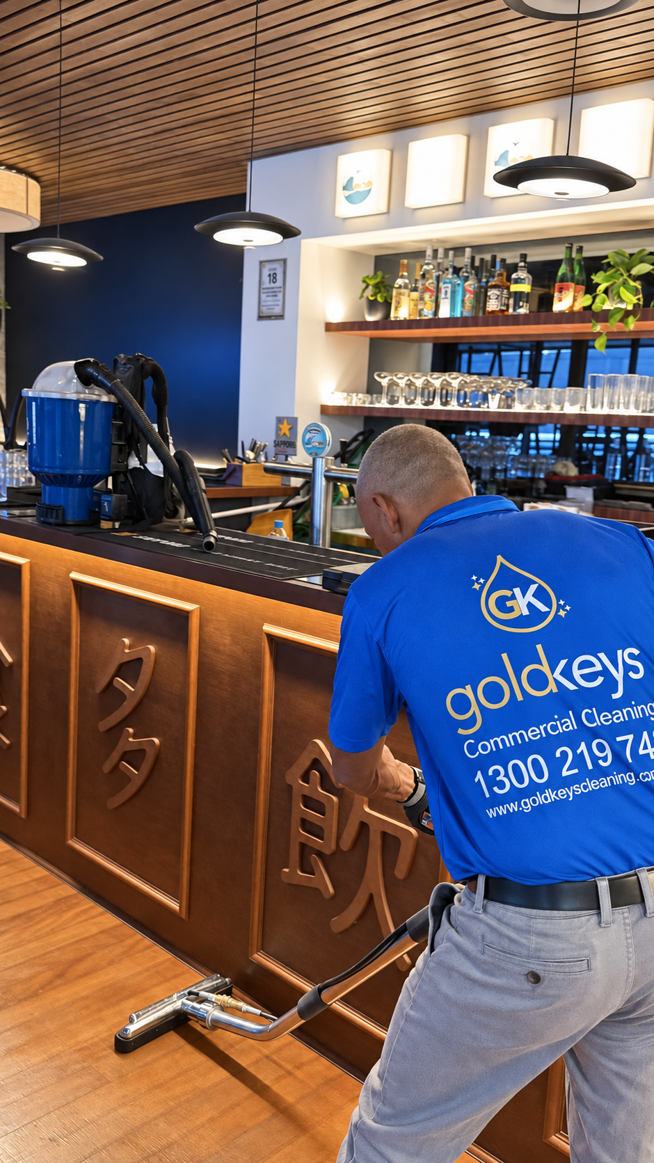 Gold Keys cleaner using floor-cleaning equipment beside a bar counter