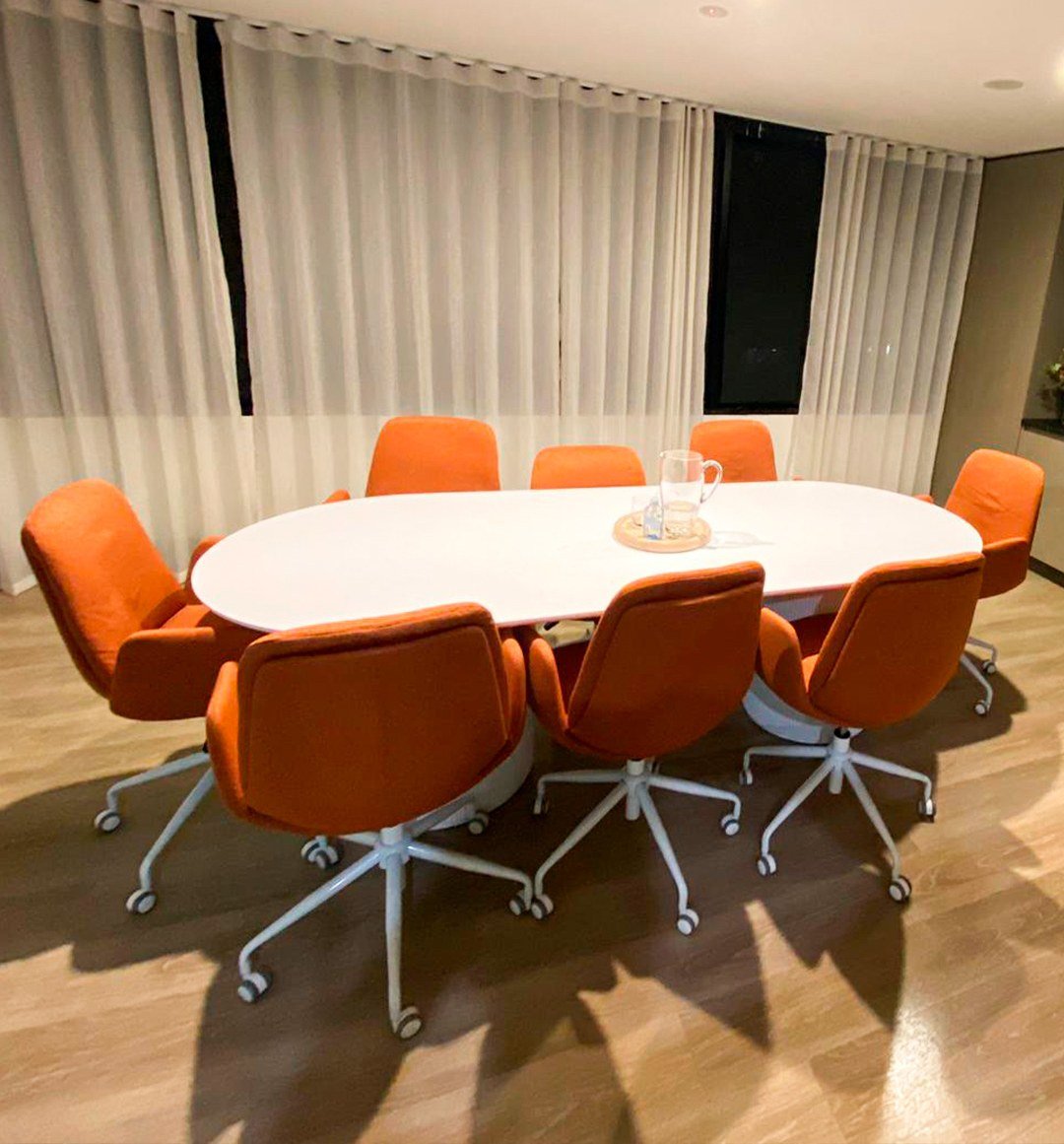 Office meeting room with orange chairs, a white table and a clean hard floor