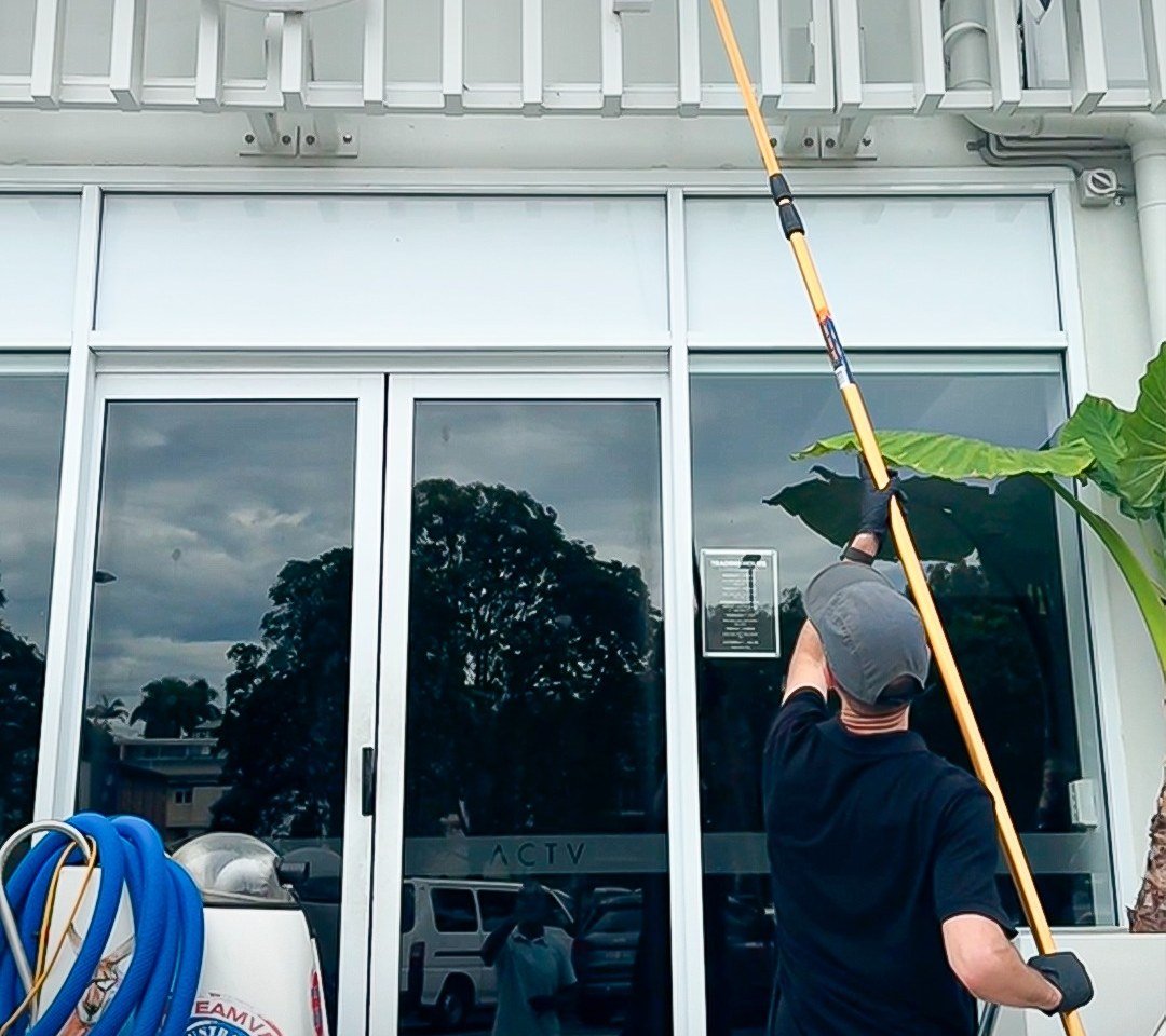 Gold Keys cleaner washing the glass entrance of a Gold Coast commercial building