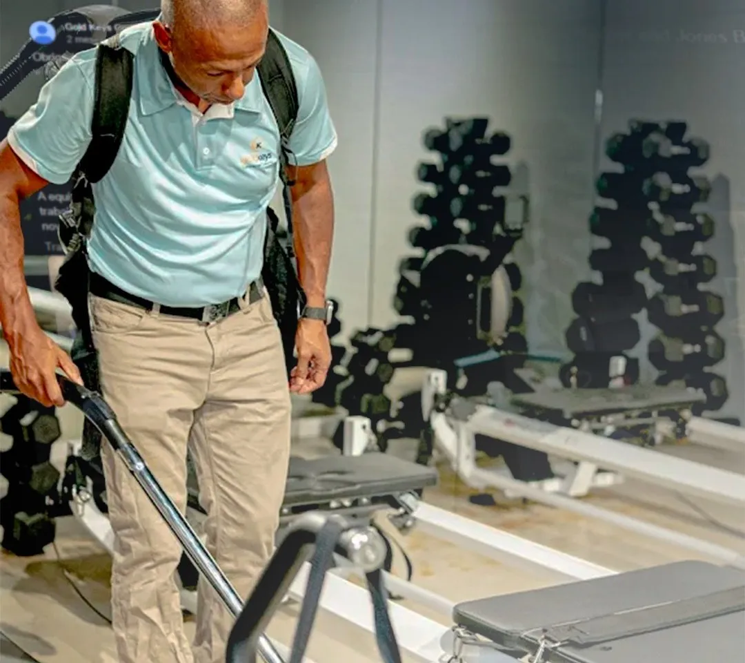 Gold Keys cleaner vacuuming a Gold Coast gym floor with a backpack vacuum
